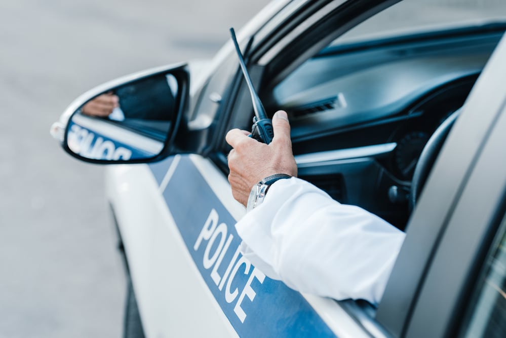 Close-up of police car window, arm hanging out with walkie talkie