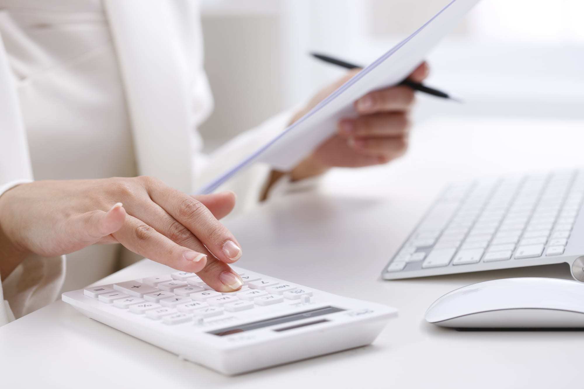 Close-up-of-typing-on-calculator-looking-at-paper