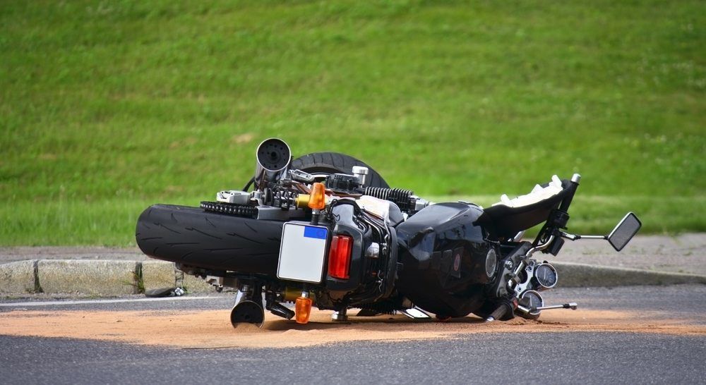 motorcycle accident on pavement, green grass behind