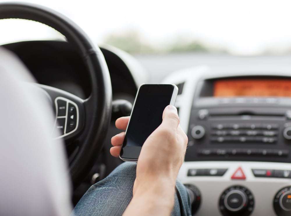 man using phone while driving car