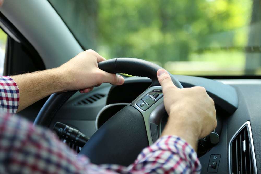 Male hands on steering wheel, driving