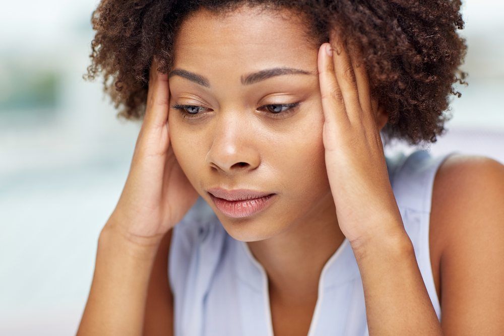 young woman touching her head and looking distressed