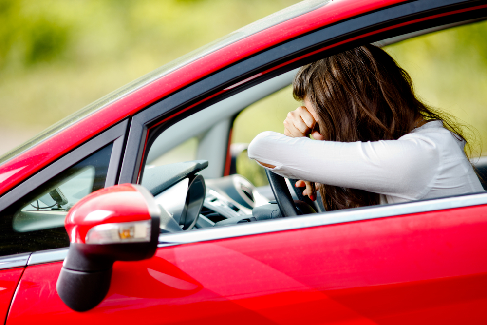 Young woman sitting in car, upset