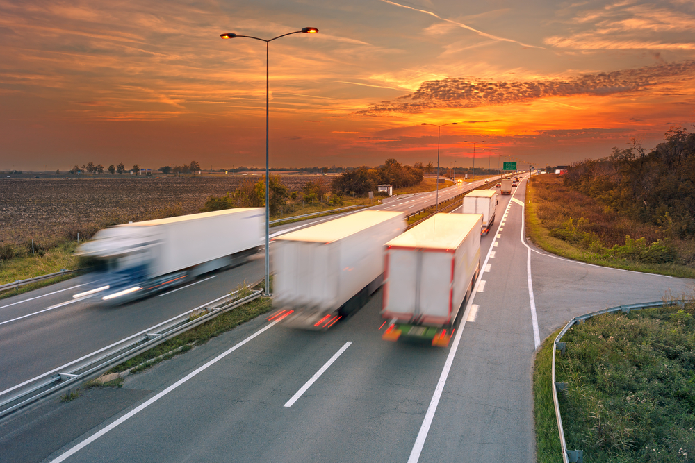 Blurred semitrucks on highway at sunset