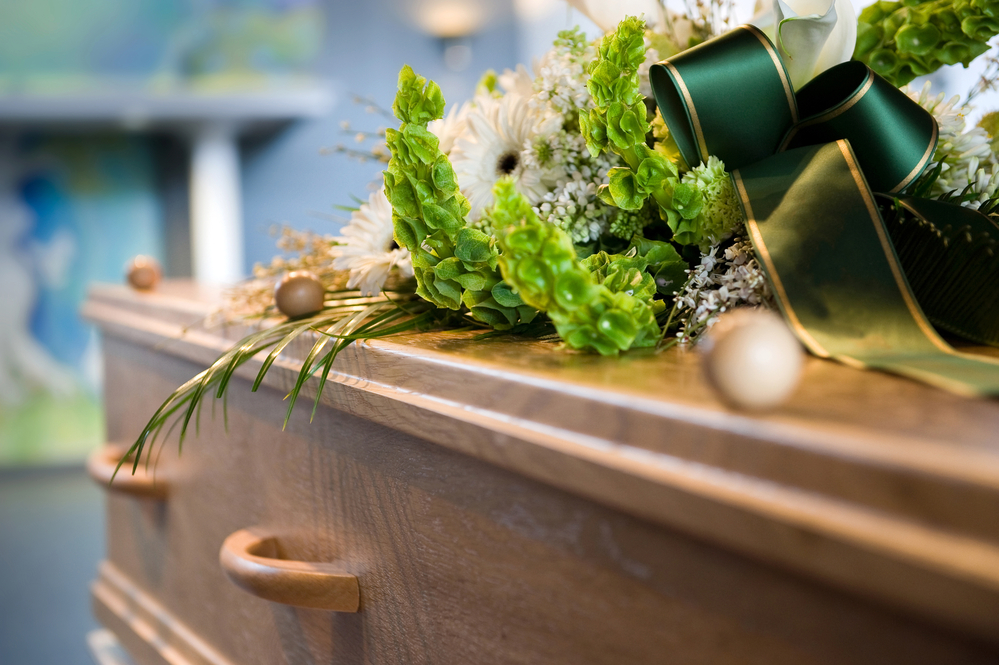 Close-up of corner of casket with green bouquet on top
