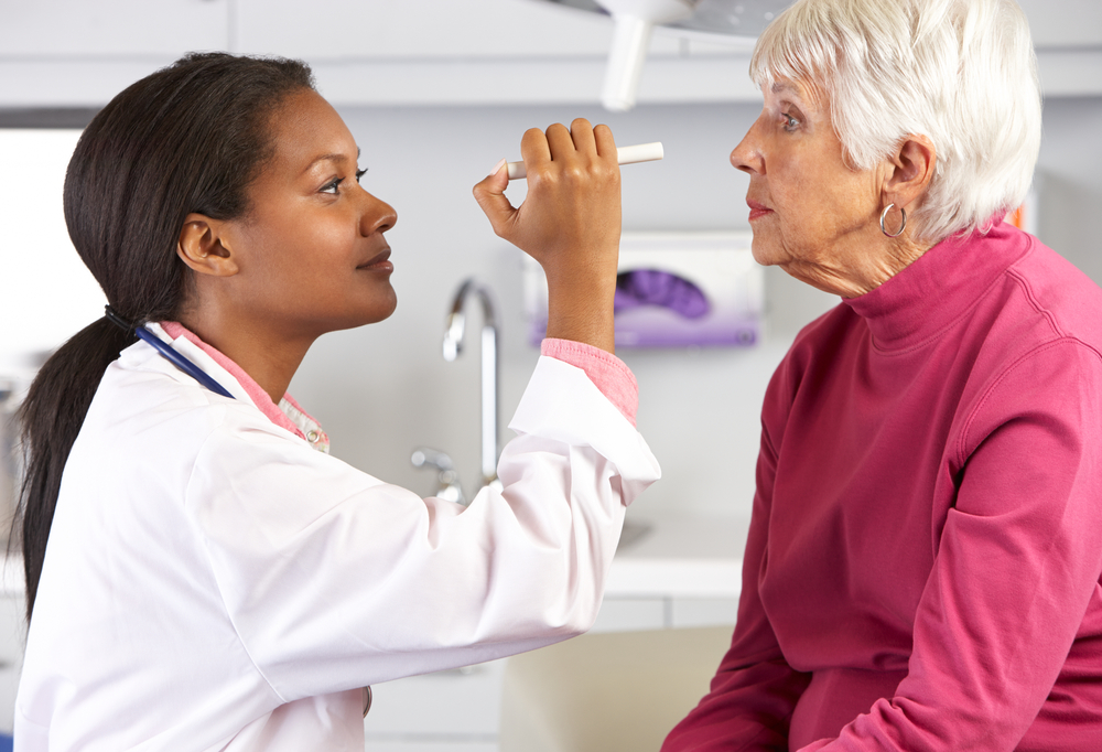 Young doctor examining eyes of senior female patient