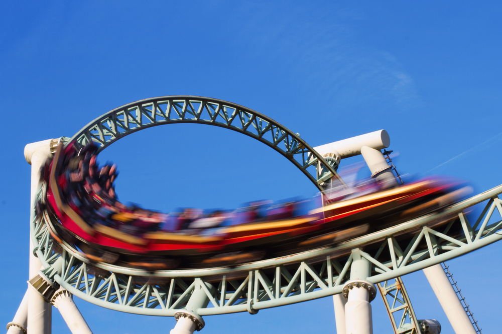 Roller coaster zooming past, blurry vehicles, blue sky