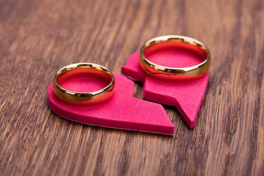 Two wedding rings on felt broken heart on table