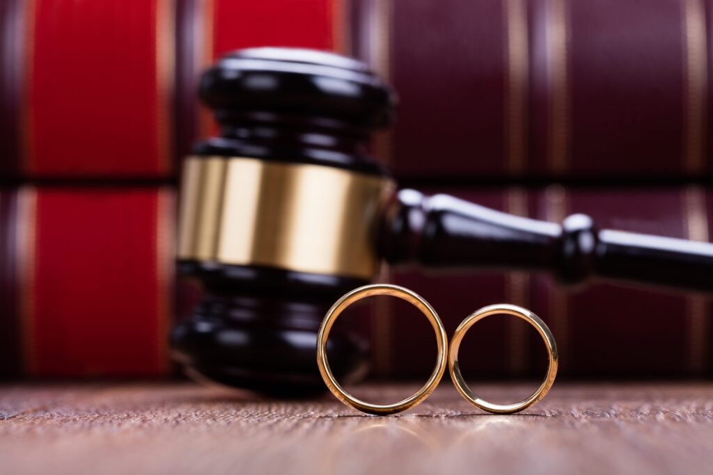 Two wedding rings balanced on their sides in front of gavel and books