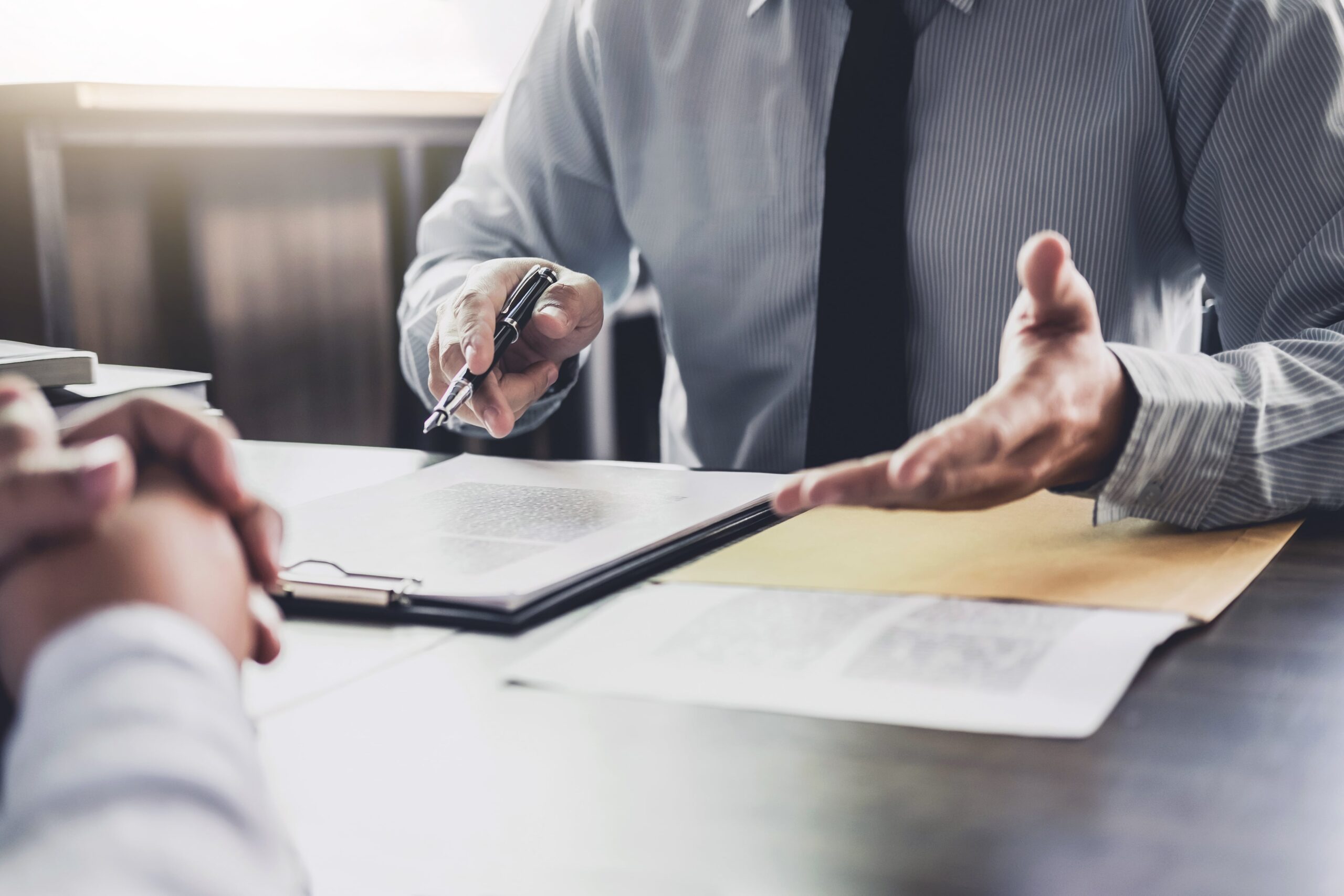Close-up of lawyer explaining something, using hands, paper on desk