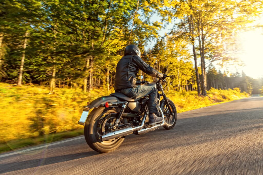 Motorcycle rider driving on road in autumn