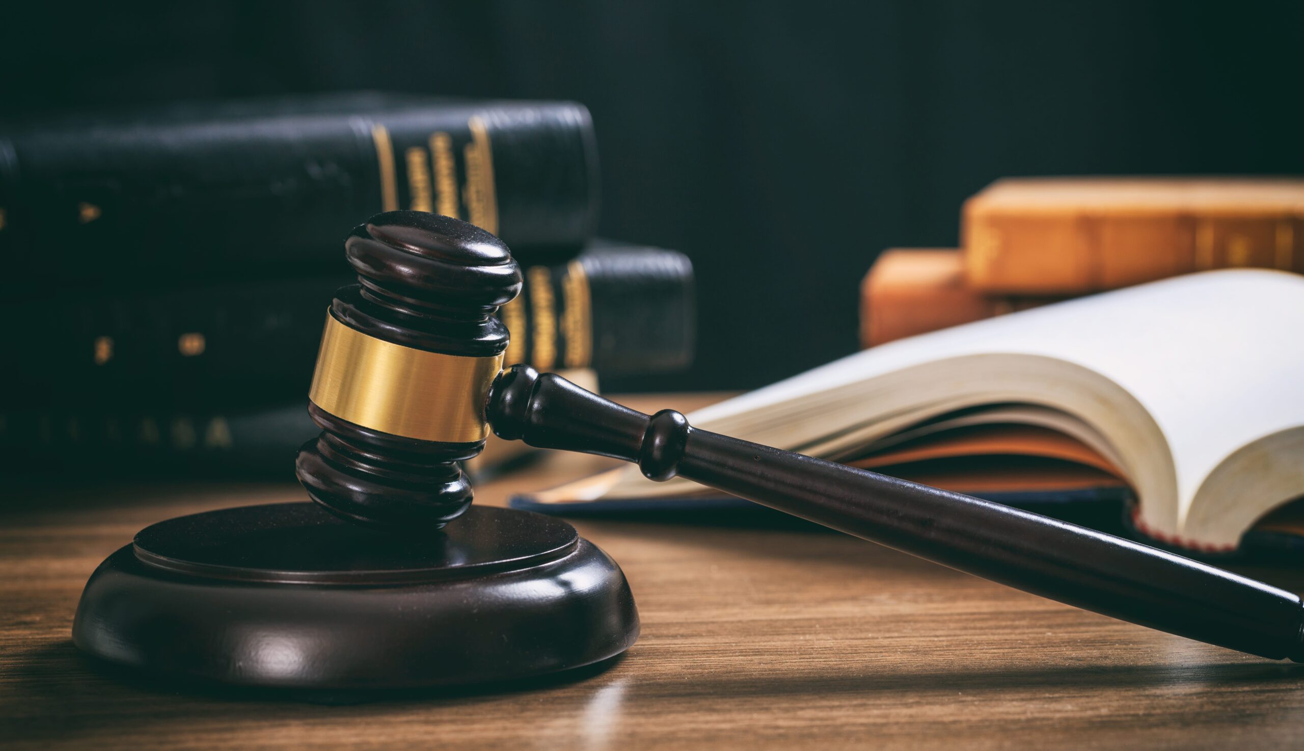 Gavel on wood desk, law books in background