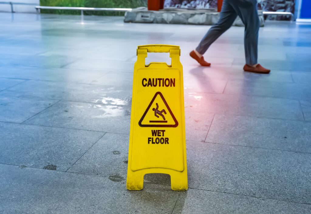 Yellow caution sign on floor, person walking in background