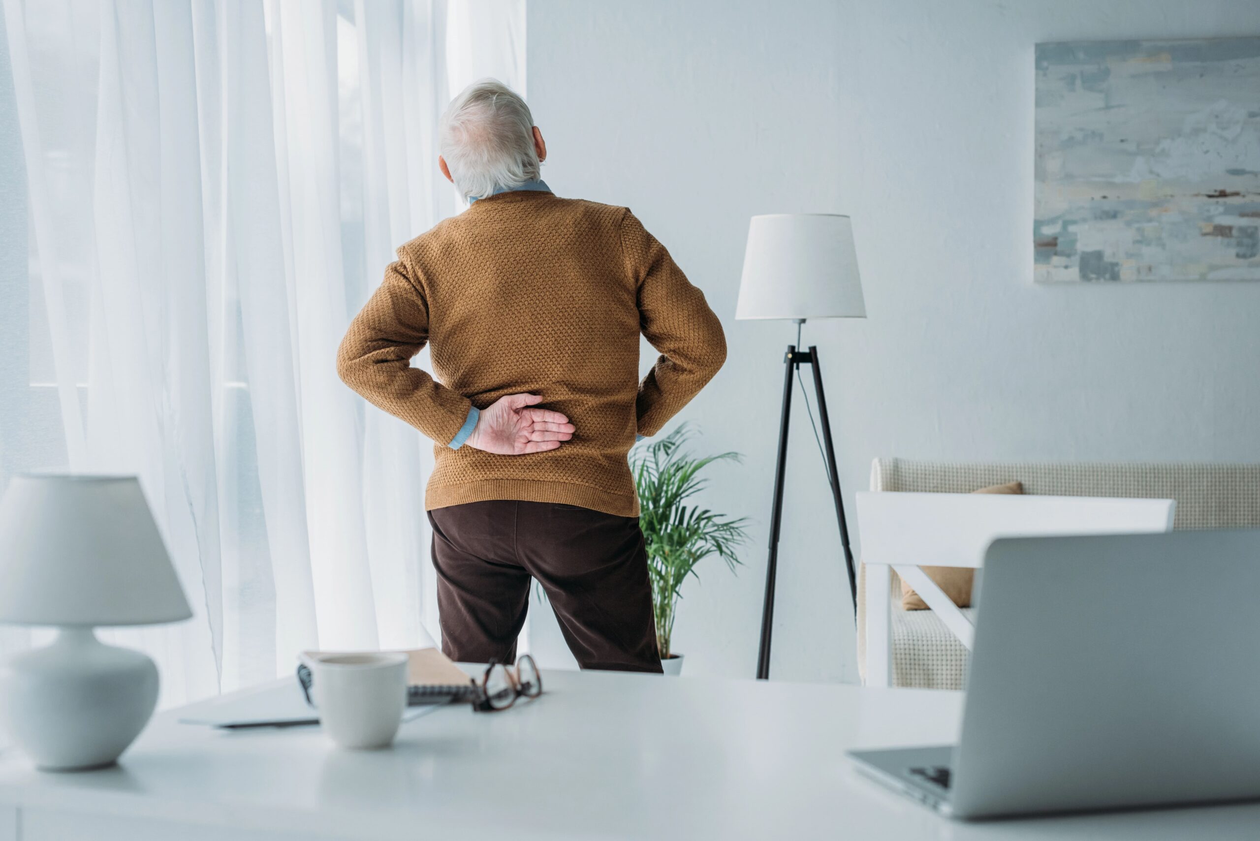 Senior man holding his lower back while standing, back pain