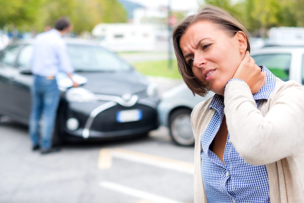 Woman holding neck, aftermath of car crash in background