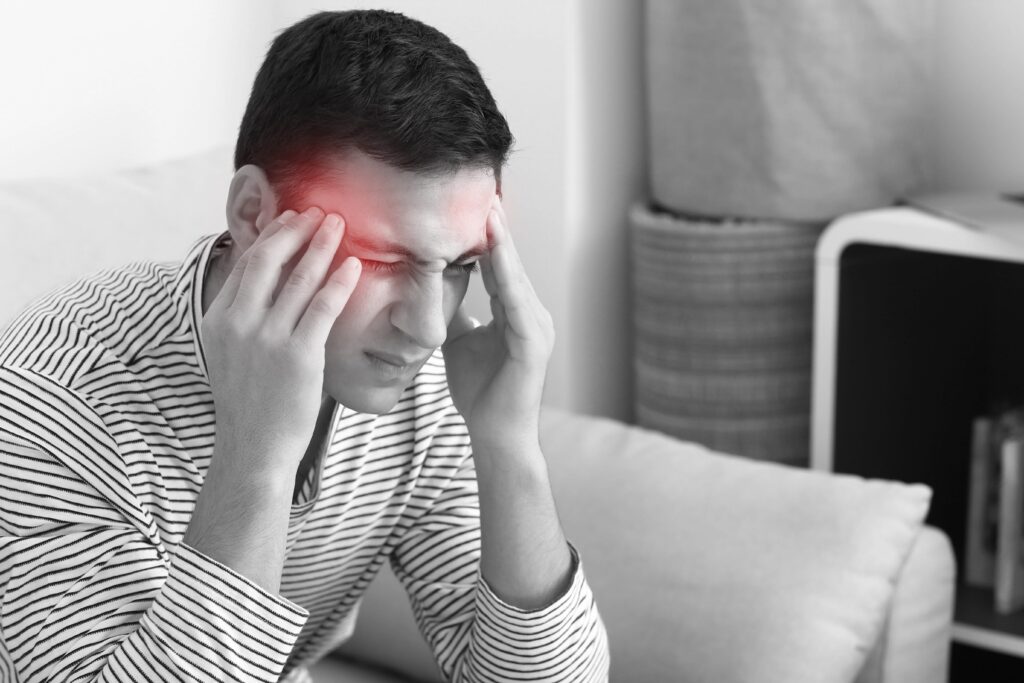 Man sitting on couch, holding head, black and white with red circle over head
