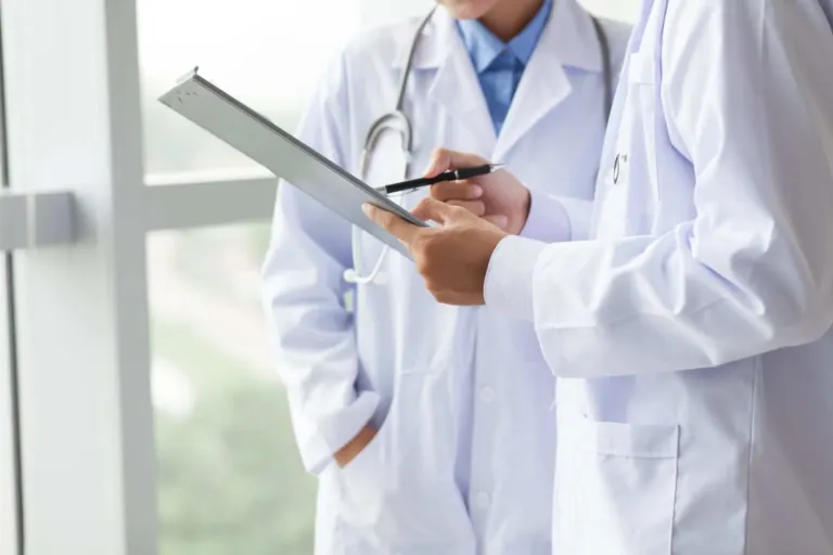 Close-up of torsos of two doctors sharing notes