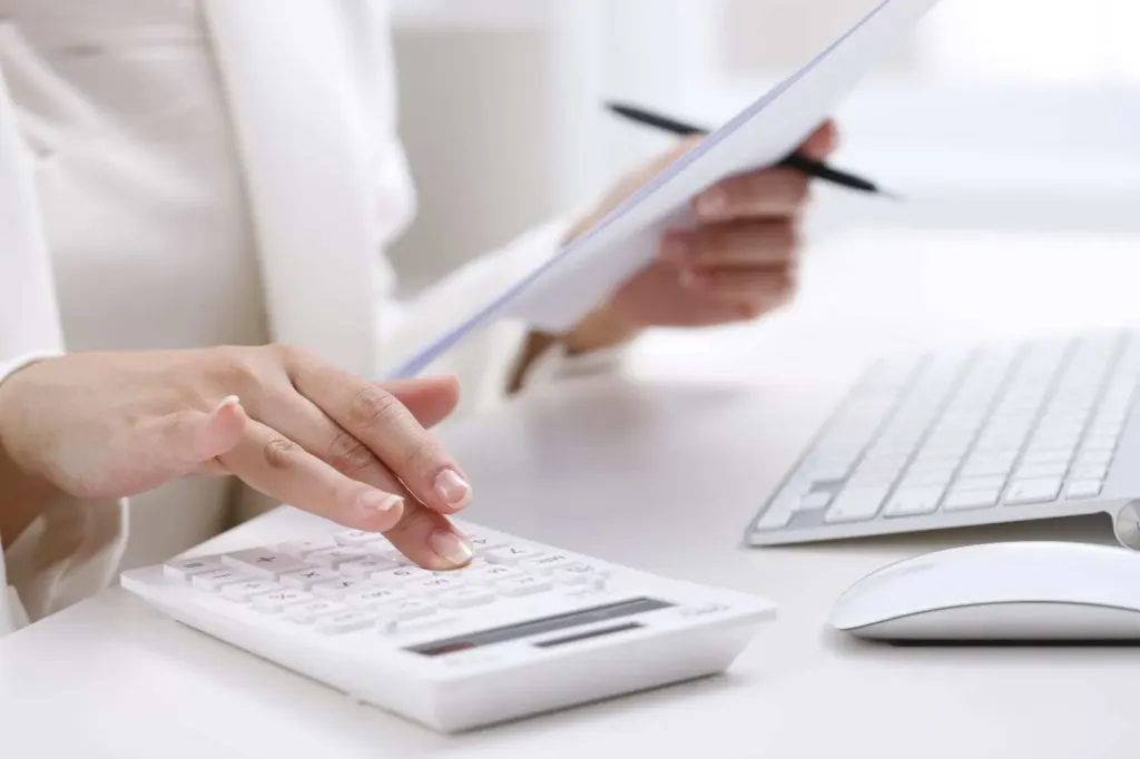 Close-up of typing on calculator looking at paper