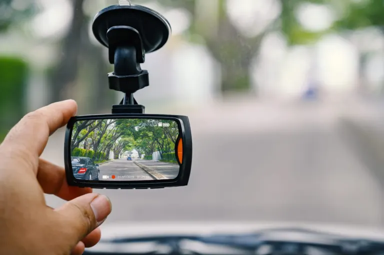 Hand adjusting dash cam in car