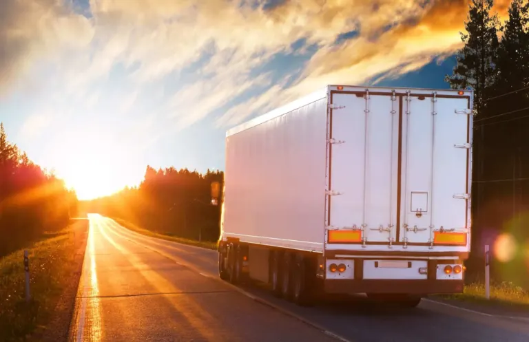 Semi-truck on asphalt road at sunset