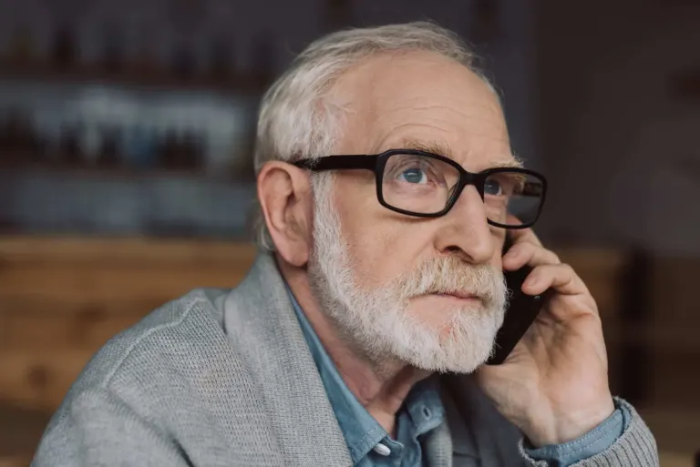 Senior Man with Serious Expression Listening to Someone on Phone