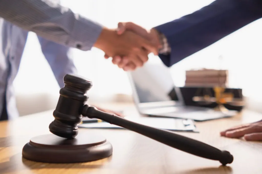 Shaking hands over legal desk with gavel