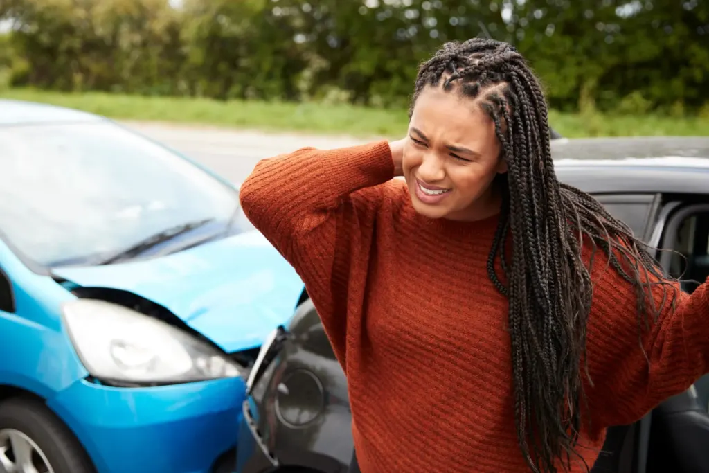 Young woman after car crash touching back of neck in pain