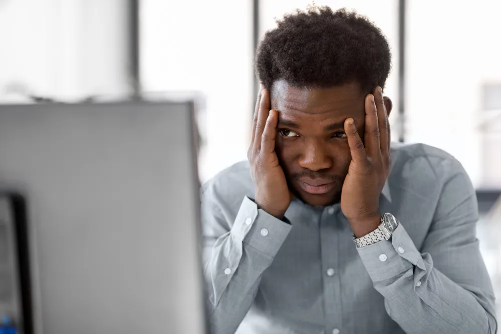 Worker holding his head in front of a computer