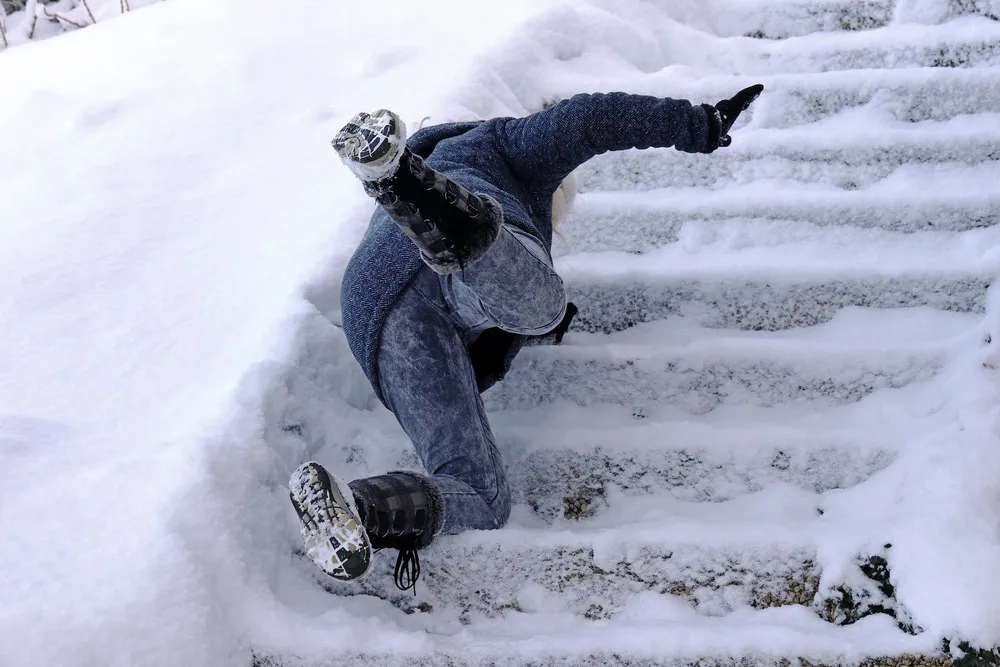Woman slipping and falling on snowy stairs