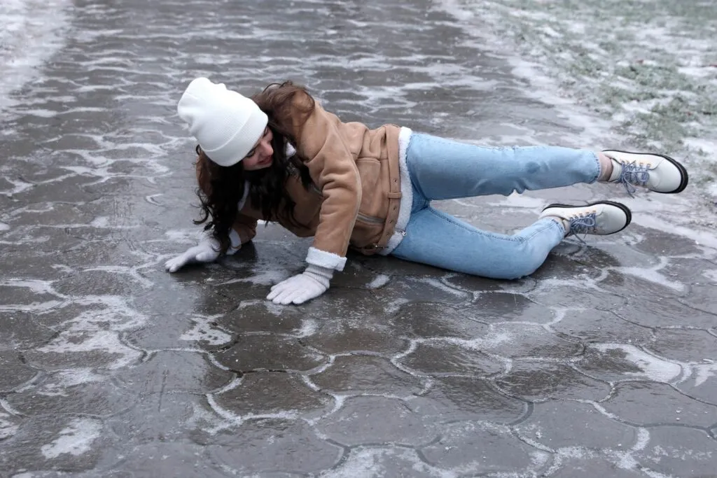 Young woman slipping on icy sidewalk